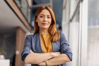 Portrait of female leader standing at corporate firm with arms crossed and smiling at camera